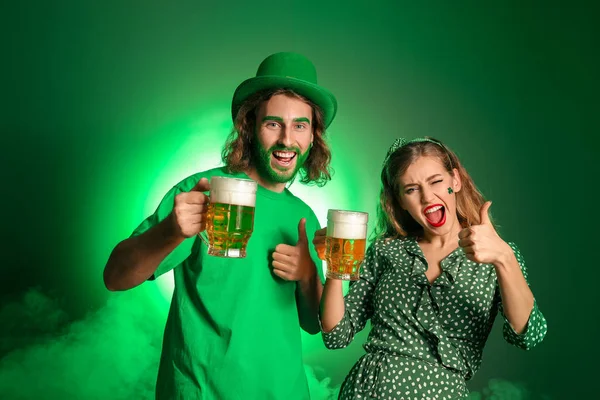 Νεαρό ζευγάρι με μπύρα στο φόντο του χρώματος. Γιορτή του Αγίου Πατρικίου — Φωτογραφία Αρχείου