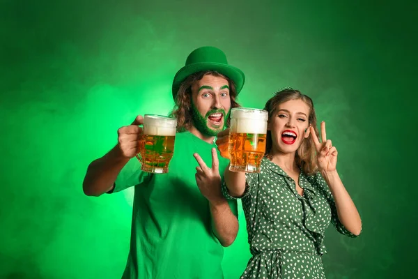 Pareja joven con cerveza sobre fondo de color. Celebración del Día de San Patricio —  Fotos de Stock