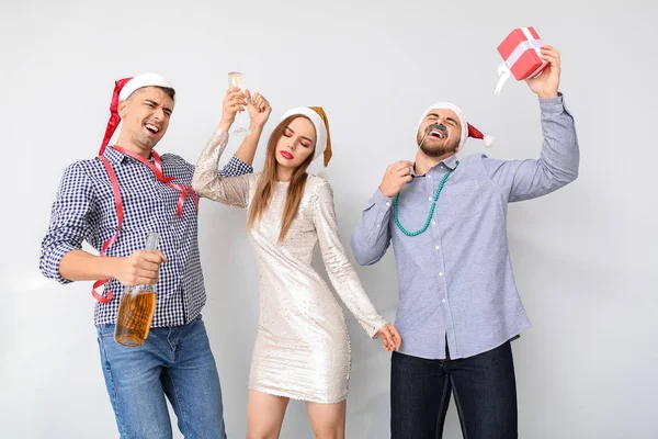 Drunk friends celebrating New Year against light background — Stock Photo, Image