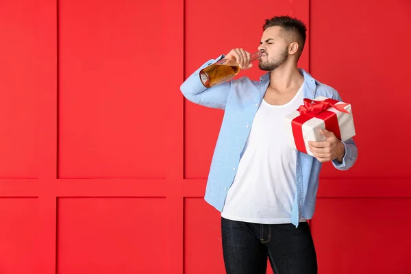 Homme ivre avec cadeau et champagne sur fond de couleur — Photo