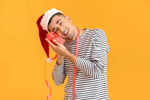 Noel Baba şapkalı sarhoş adam ve renkli bir hediye. — Stok fotoğraf