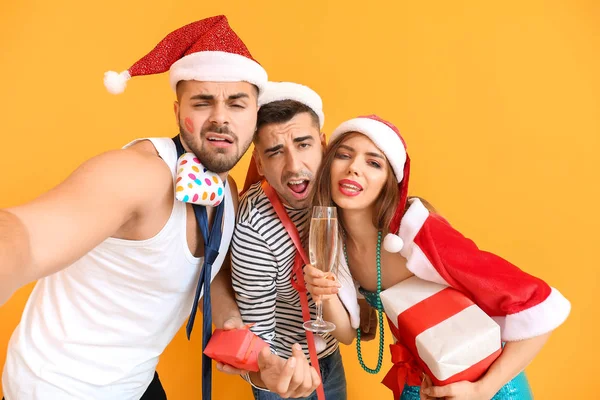 Drunk friends taking selfie during celebrating New Year against color background — Stock Photo, Image