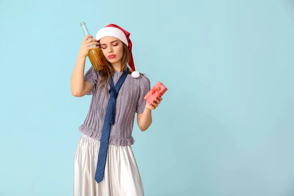 Femme ivre dans le chapeau du Père Noël, avec champagne et cadeau sur fond de couleur — Photo