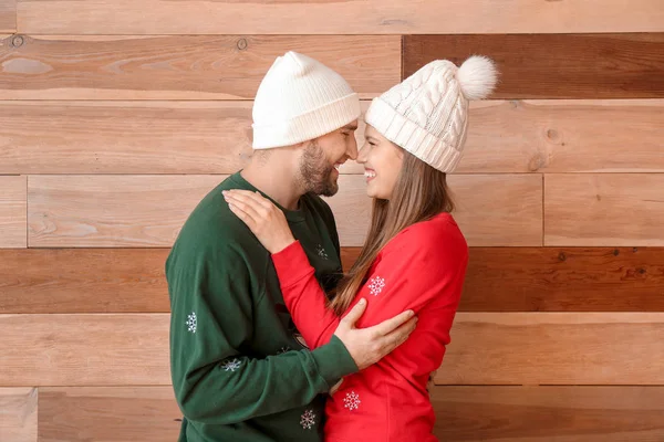 Portrait of happy couple in Christmas clothes on wooden background — Stock Photo, Image