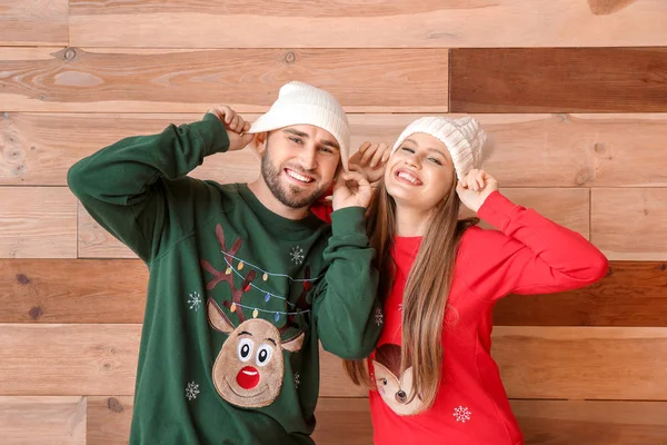 Portrait of happy couple in Christmas clothes on wooden background — Stock Photo, Image
