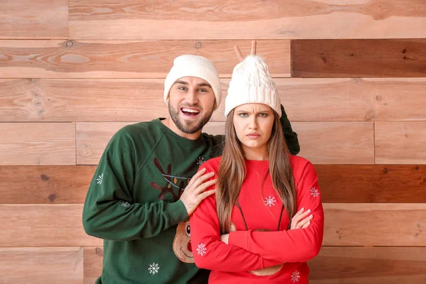 Portrait of emotional couple in Christmas clothes on wooden background — 스톡 사진