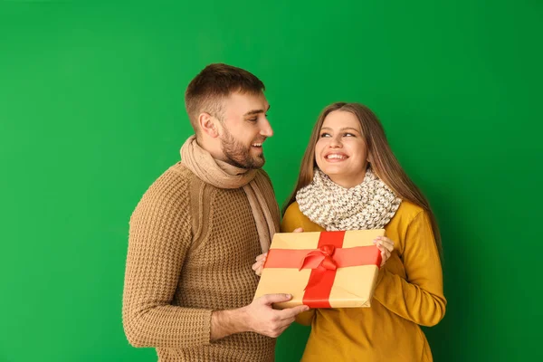 Happy man giving present to his girlfriend against color background — Stock Photo, Image