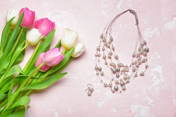 Beautiful tulip flowers with jewelry on color background. International Women's Day celebration — Stock Photo, Image