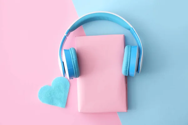 Libro y auriculares modernos sobre fondo de color. Concepto de audiolibro —  Fotos de Stock