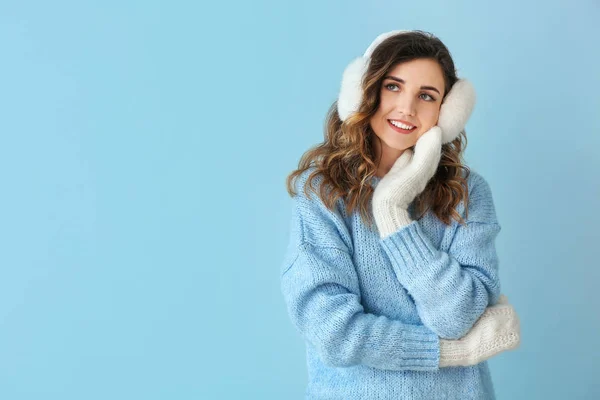 Beautiful young woman in warm sweater and mittens on color background — 스톡 사진