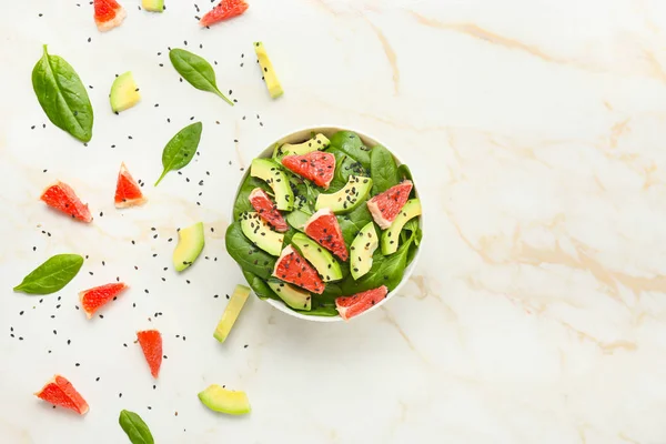 Schaal met lekkere salade en ingrediënten op lichte achtergrond — Stockfoto