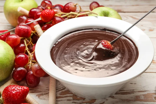 Trempage de fraises savoureuses dans un bol avec fondue au chocolat sur la table — Photo