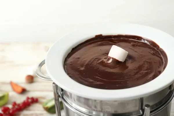 Dipping of tasty marshmallow into bowl with chocolate fondue on table, closeup — Stock Photo, Image
