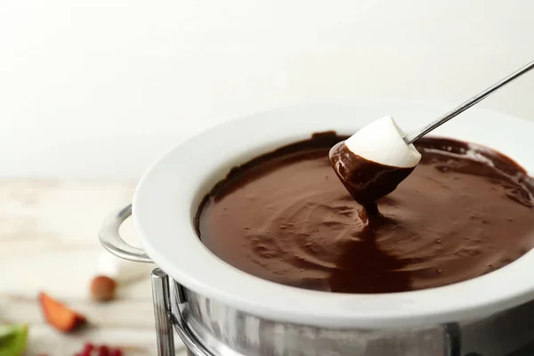 Dipping of tasty marshmallow into bowl with chocolate fondue on table, closeup — Stock Photo, Image