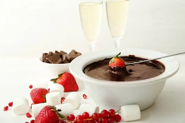 Dompelen van smakelijke aardbei in kom met chocoladefondue op tafel — Stockfoto