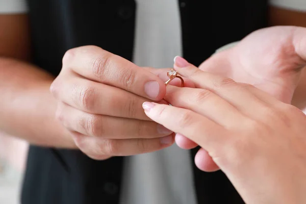 Young man putting ring on finger of his fiancee after marriage proposal, closeup Stock Image
