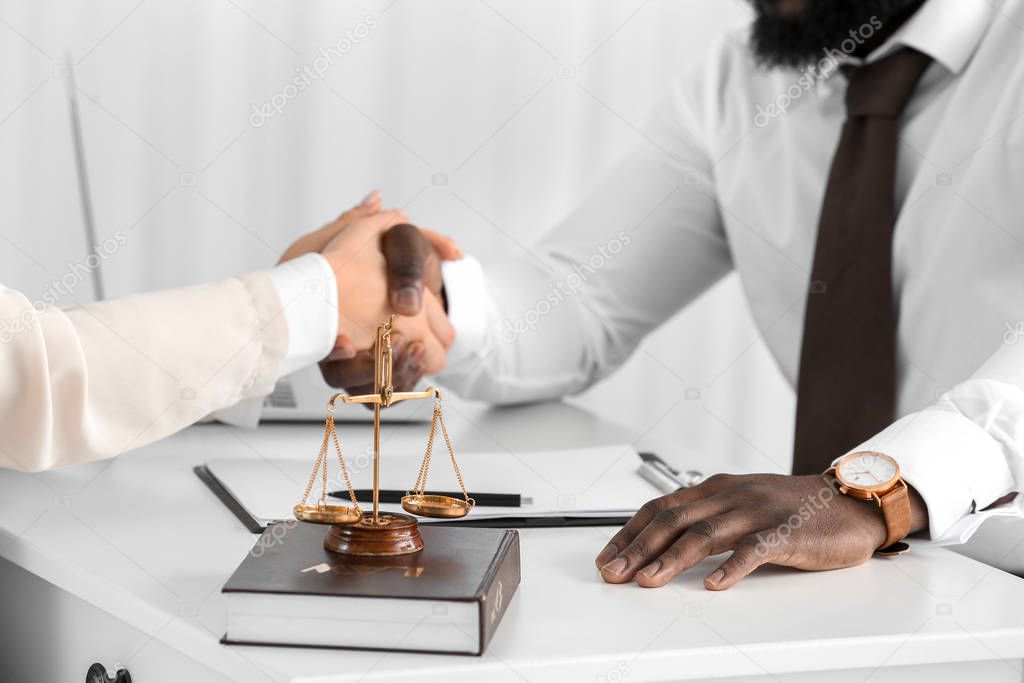 Woman and lawyer shaking hands in office