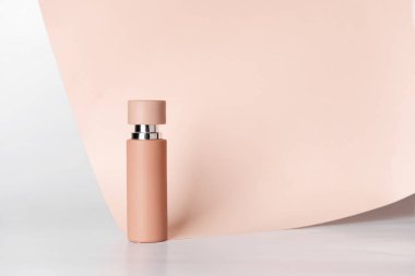 Beyaz arka planda kağıt yaprağı olan bir şişe parfüm.