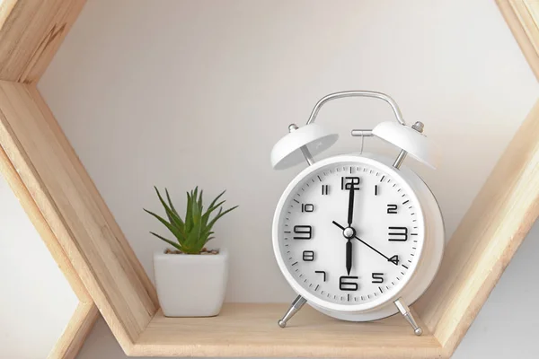 Relógio despertador com planta na prateleira pendurada na parede — Fotografia de Stock