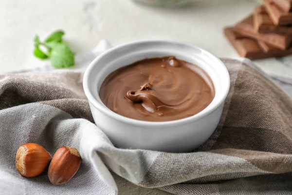 Mangkuk dengan pasta coklat lezat dan hazelnut di atas meja — Stok Foto