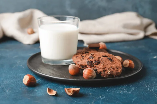 Tasty chocolate cookies with hazelnuts and glass of milk on dark background — Stock Photo, Image