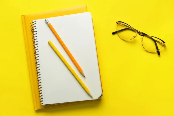 Notebook alla moda con matite e occhiali su sfondo a colori — Foto Stock