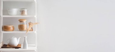 Beyaz duvarın yanındaki raflarda, metin için yeri olan mutfak eşyaları.