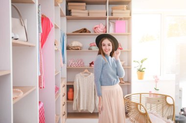 Güzel, genç bir kadın büyük gardıroptan kıyafet seçiyor.