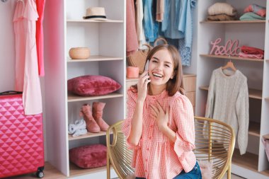 Soyunma odasında telefonla konuşan güzel genç bir kadın.