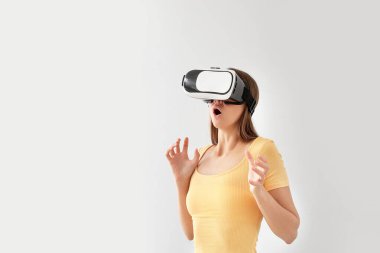 Işık arka planında sanal gerçeklik gözlüklü genç bir kadın.