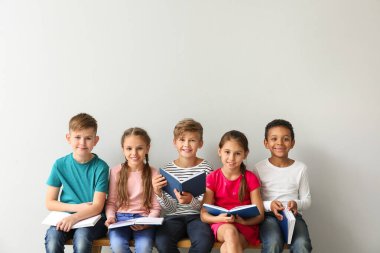 Cute little children reading books on grey background