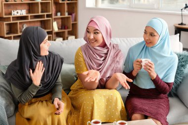 Güzel, genç Müslüman kadınlar evde çay içiyor.