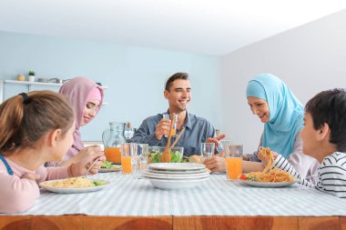 Müslüman bir aile evde yemek yiyor.