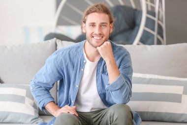 Evdeki kanepede oturan yakışıklı adam.