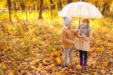 Sonbahar parkında şemsiyeli şirin çocuklar.