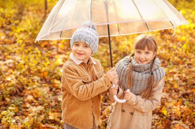 Sonbahar parkında şemsiyeli şirin çocuklar.