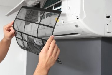 Erkek teknisyen içeride klimayı tamir ediyor, yakın plan.