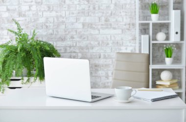 Modern odada dizüstü bilgisayarı olan şık ve rahat bir iş yeri.