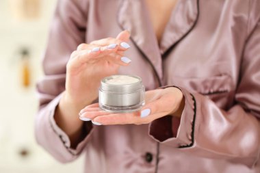 Banyoda krema dolu kavanozu olan genç ve güzel bir kadın.