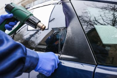 Erkek işçi araba camını boyuyor.