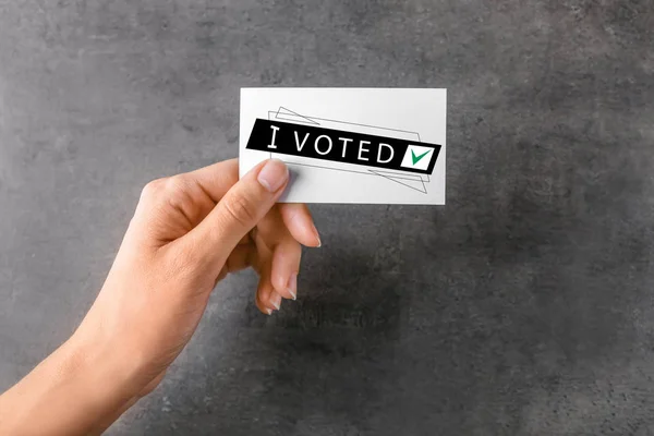 Kvinna innehav kort med text I Röstade på grå bakgrund — Stockfoto