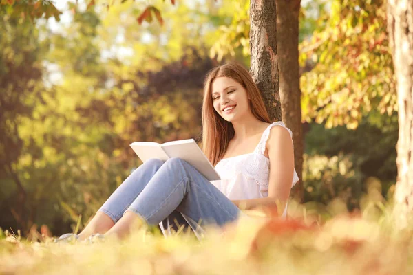 Vacker ung kvinna läser bok i parken — Stockfoto