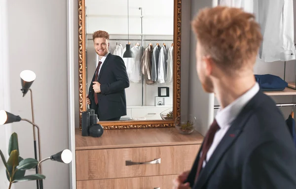 Handsome man trying on stylish clothes in dressing room — Stock Photo, Image