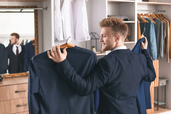 Handsome man choosing clothes in dressing room — Stock Photo, Image