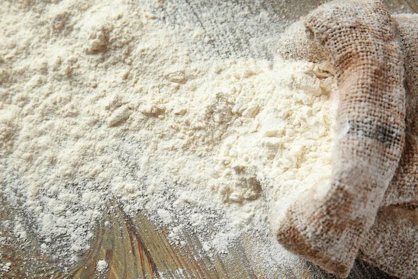 Bag with scattered flour on wooden table — Stock Photo, Image