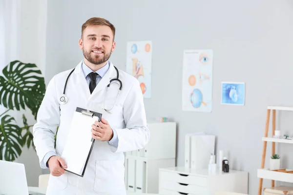 Portrait of male doctor with clipboard in clinic — Stock Photo, Image