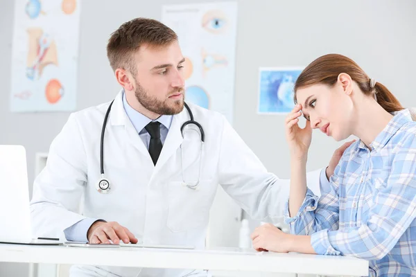 Male doctor calming sad female patient in clinic