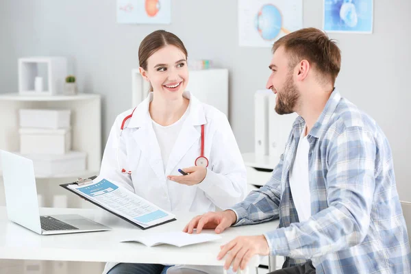 Médico femenino que trabaja con paciente masculino en clínica — Foto de Stock