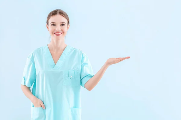 Portrét ženského lékaře zobrazující něco na světlém pozadí — Stock fotografie