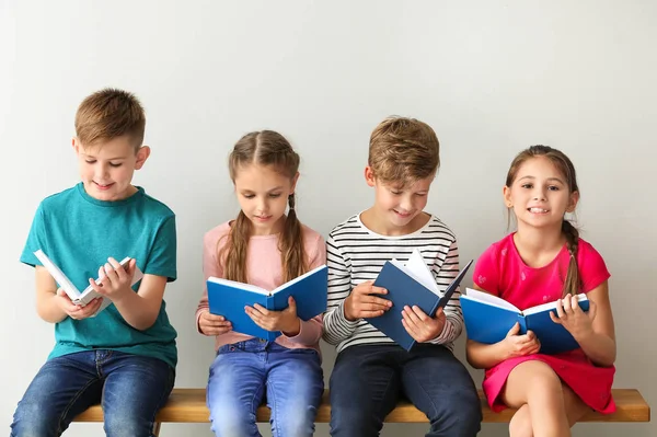 Niedliche kleine Kinder lesen Bücher auf grauem Hintergrund — Stockfoto